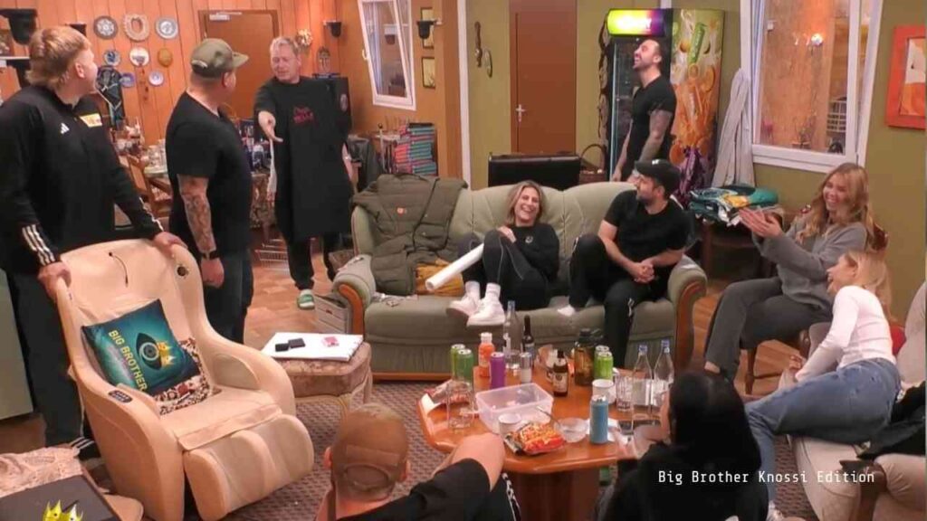 Eine Gruppe von Menschen in einem Raum, die sich um eine Couch versammelt haben, während sie miteinander interagieren.