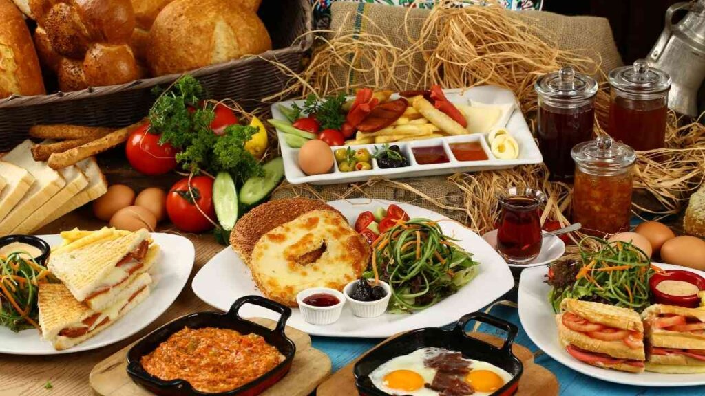 Ein reichhaltiges Frühstücksarrangement mit verschiedenen Speisen, darunter Sandwiches, Eier, Gemüse und Marmelade.