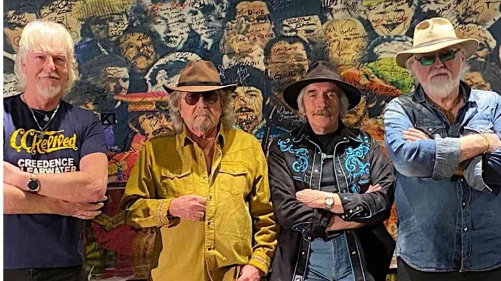 Die Band Creedence Clearwater Revived posieren mit Johnnie Guitar Williamson vor einer bunten Wand