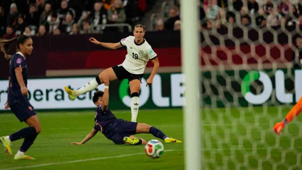 Spielerin der deutschen Frauenfußballnationalmannschaft während eines Spiels, mit einem Gegner am Boden.