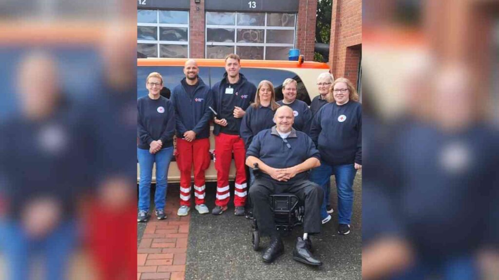 Gruppe von Mitarbeitenden in Uniformen vor einem Krankenwagen, lächelnd und bereit für den Einsatz.