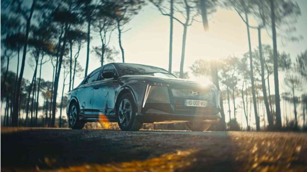 Schwarzes Auto mit modernem Design, das auf einer Straße zwischen Bäumen steht, bei Sonnenuntergang beleuchtet.