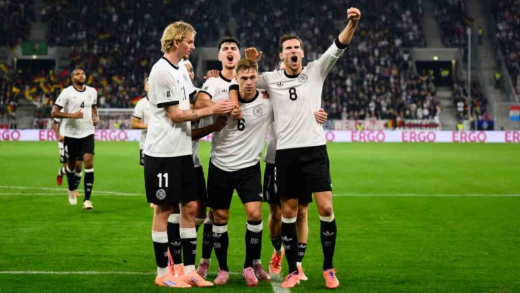 Deutsche Fußballspieler feiern ein Tor während eines Spiels in einem Stadion.