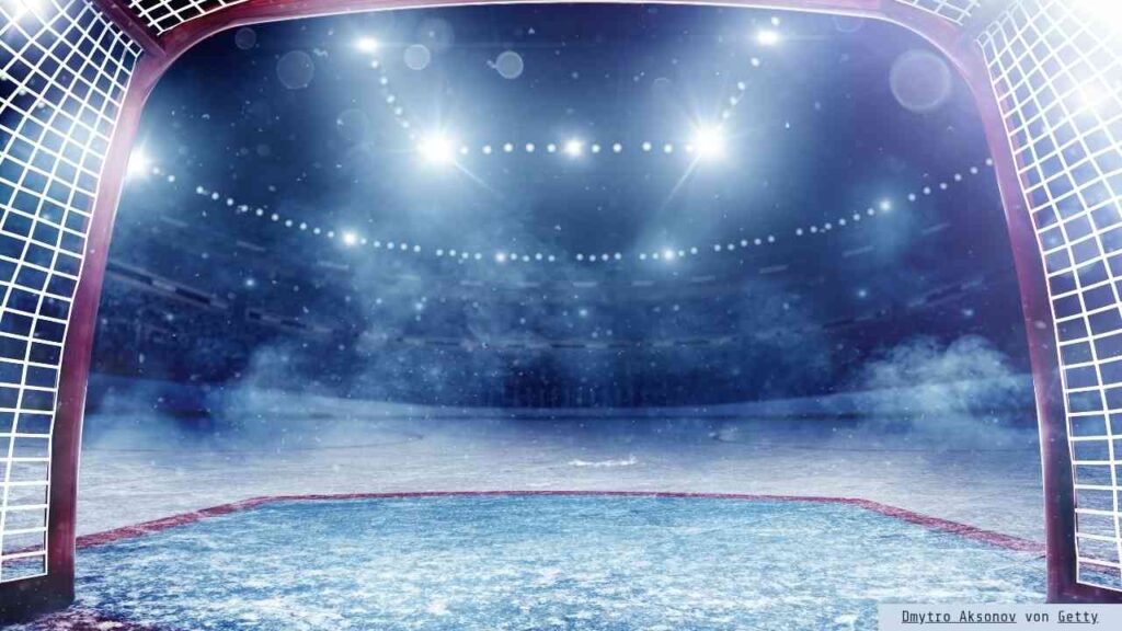 Eishockeytor mit beleuchtetem Eisfeld und verschwommenem Hintergrund in einer Sportarena.