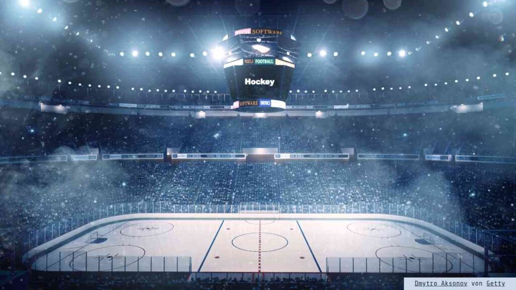 Eishockey-Arena mit beleuchtetem Spielfeld und Zuschauern im Hintergrund während eines Spiels.