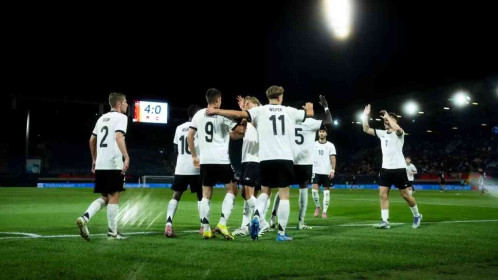 Eine Fußballmannschaft in weißen Trikots feiert ein Tor während eines Spiels im Stadion.