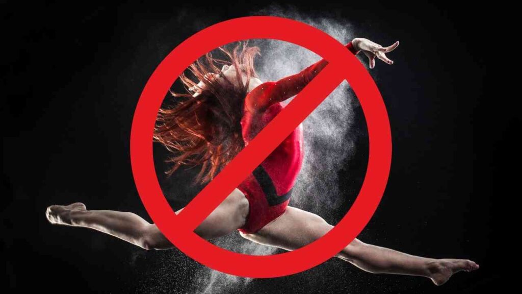 Turnerin in rotem Anzug springt in einer dynamischen Pose mit Staubwolke im Hintergrund.