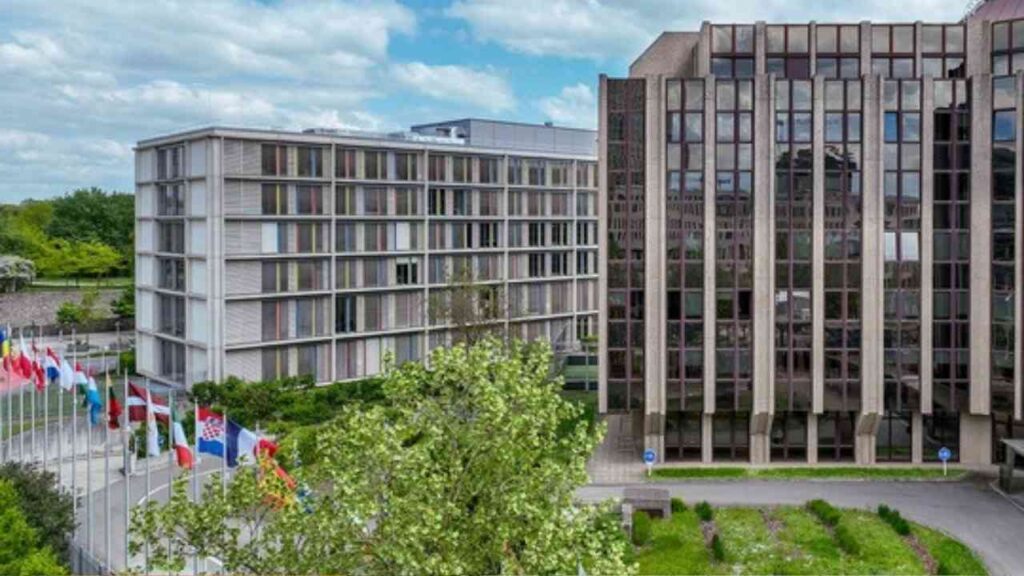 Das Gebäude des Europäischen Rechnungshofs mit Flaggen verschiedener Länder im Vordergrund.