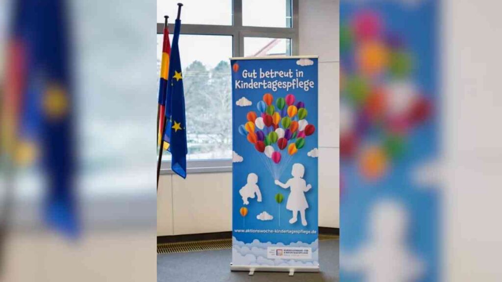 Roll-up-Banner mit dem Slogan 'Gut betreut in Kindertagespflege' und bunten Luftballons auf blauem Hintergrund.
