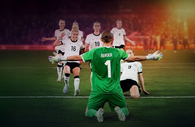 Torhüterin Berger mit der Nummer 1, kniend, während Teamkolleginnen im Hintergrund jubeln.