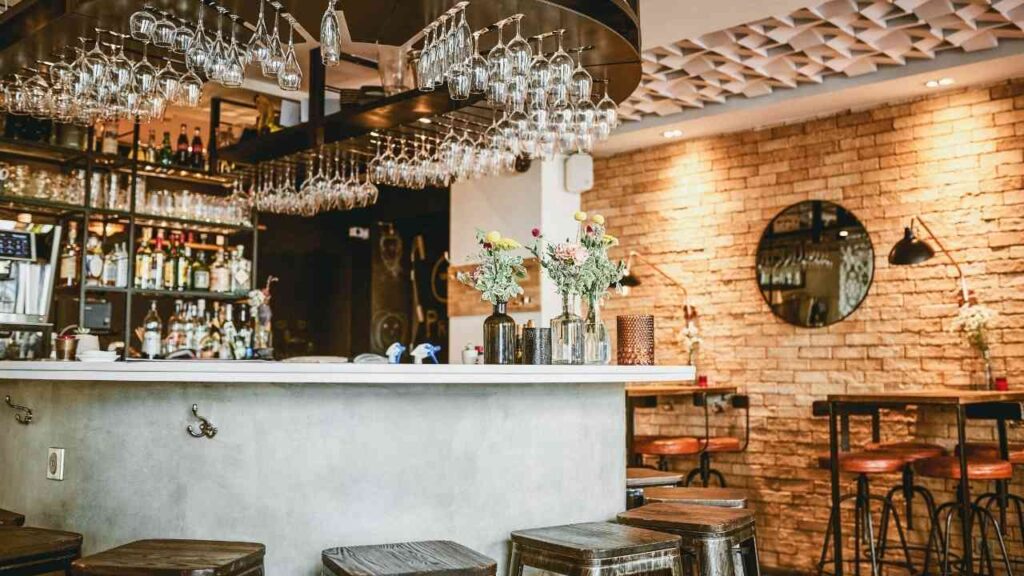 Moderne Bar mit Gläsern, einer Theke aus Beton und Holzstühlen in einem stilvollen Ambiente.