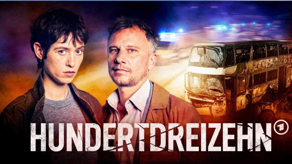 Zwei Hauptdarsteller aus der Serie 'Hundertdreizehn' vor einem beschädigten Doppeldeckerbus.