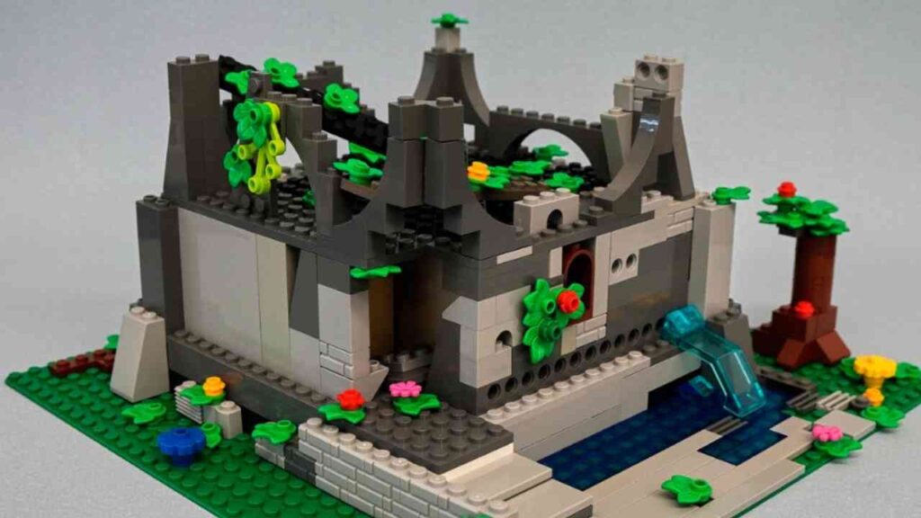 Lego-Ruine mit Pflanzen und Wasserfall, umgeben von grüner Landschaft. Kreative Architektur aus bunten Bausteinen.