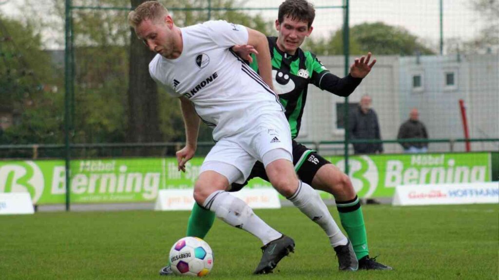 Zwei Fußballspieler im Wettkampf um den Ball auf einem Spielfeld während eines Spiels.