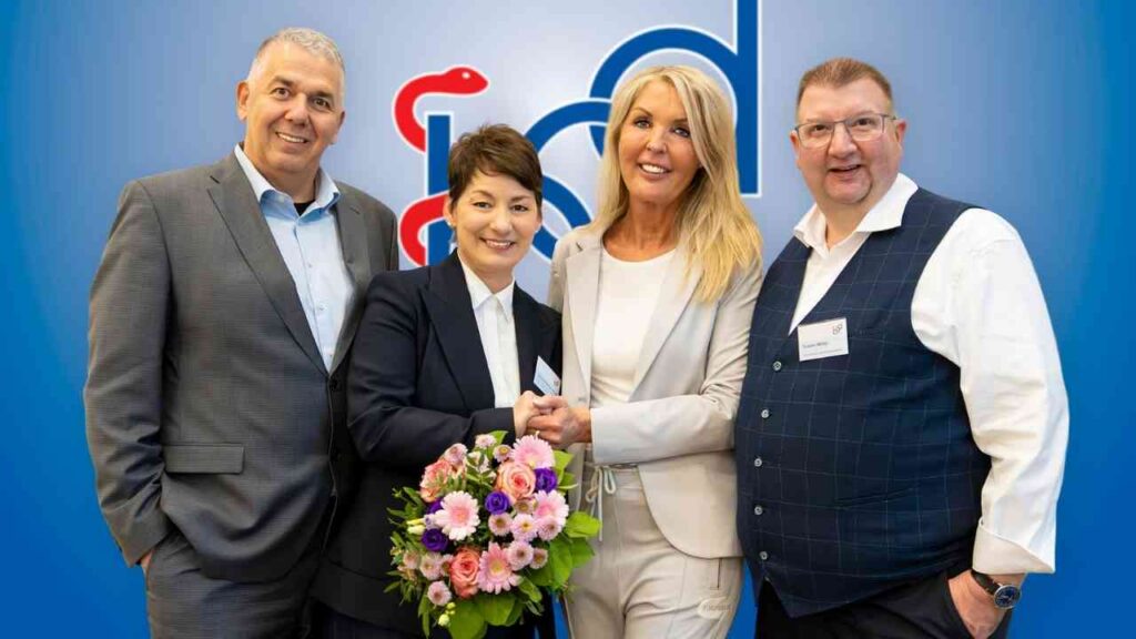 Vier Personen stehen zusammen und halten einen Blumenstrauß in einer Indoor-Umgebung.