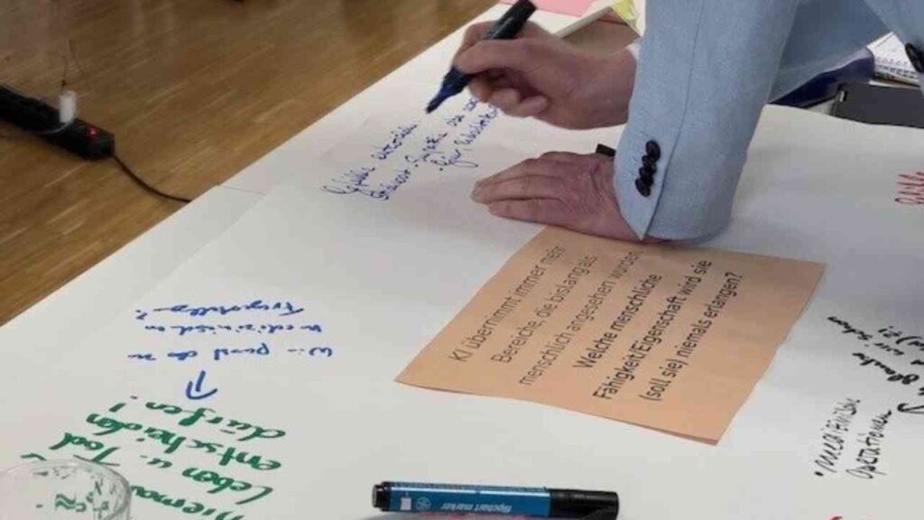 Hand, die mit einem Marker auf einem großen Blatt Papier Notizen und Ideen während eines Seminars macht.