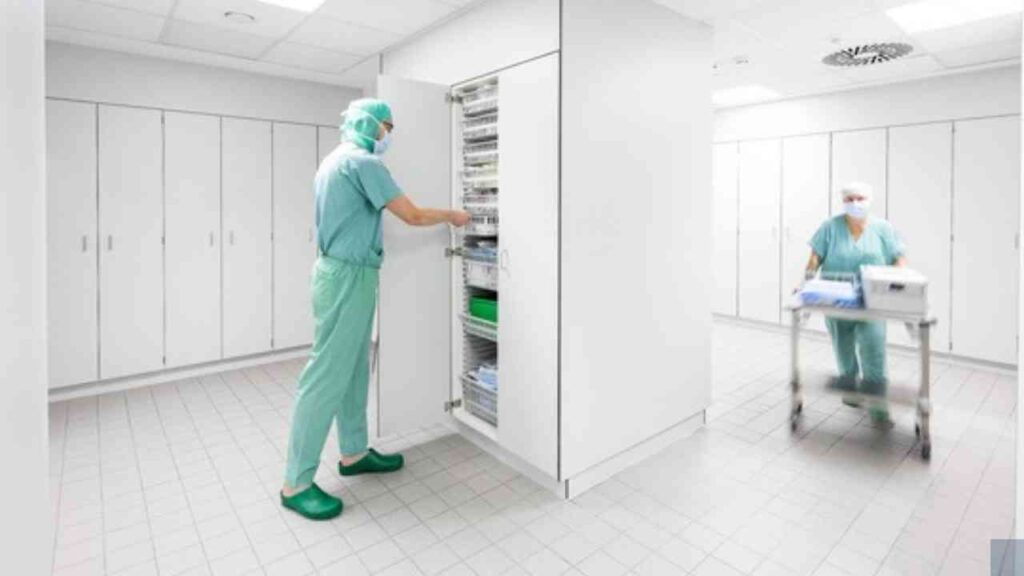 Medizinisches Personal in OP-Kleidung, das einen Schrank mit medizinischen Vorräten im Krankenhaus öffnet.