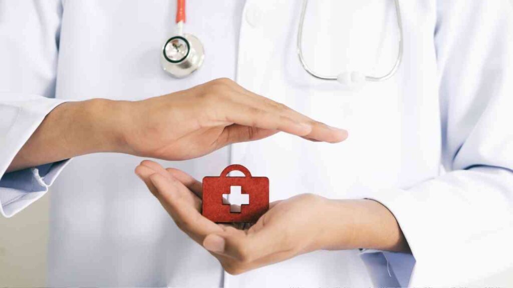 Hände eines Arztes, die ein rotes medizinisches Symbol in Form eines Koffers halten.