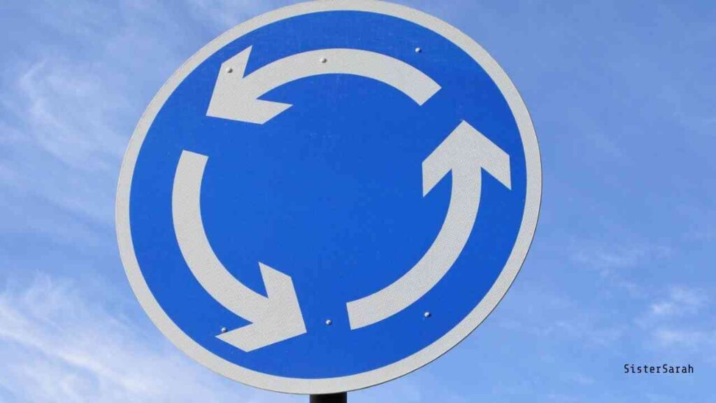 Verkehrszeichen für einen Kreisverkehr mit blauen Hintergrund und weißen Pfeilen, die im Kreis zeigen.