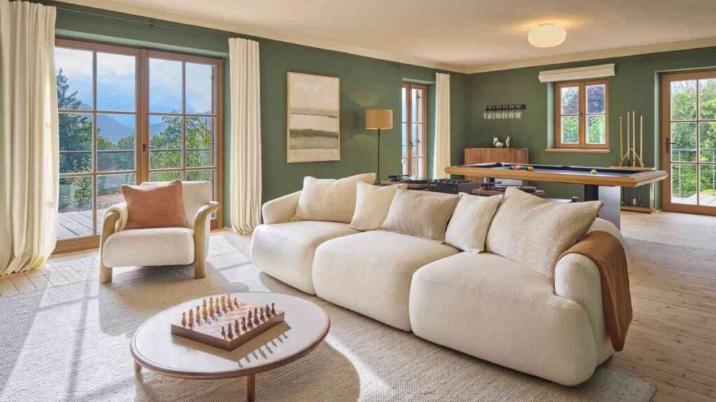 Helles Wohnzimmer mit einem modernen, beigen Sofa und einem Schachspiel auf einem Tisch.