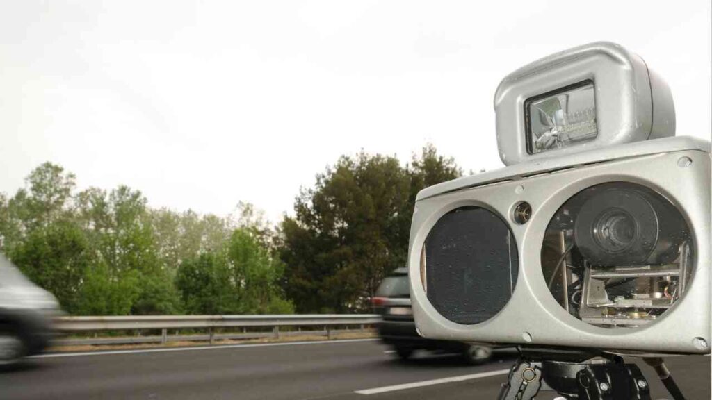 Mobiler Blitzer auf einer Autobahn mit vorbeifahrenden Fahrzeugen im Hintergrund.