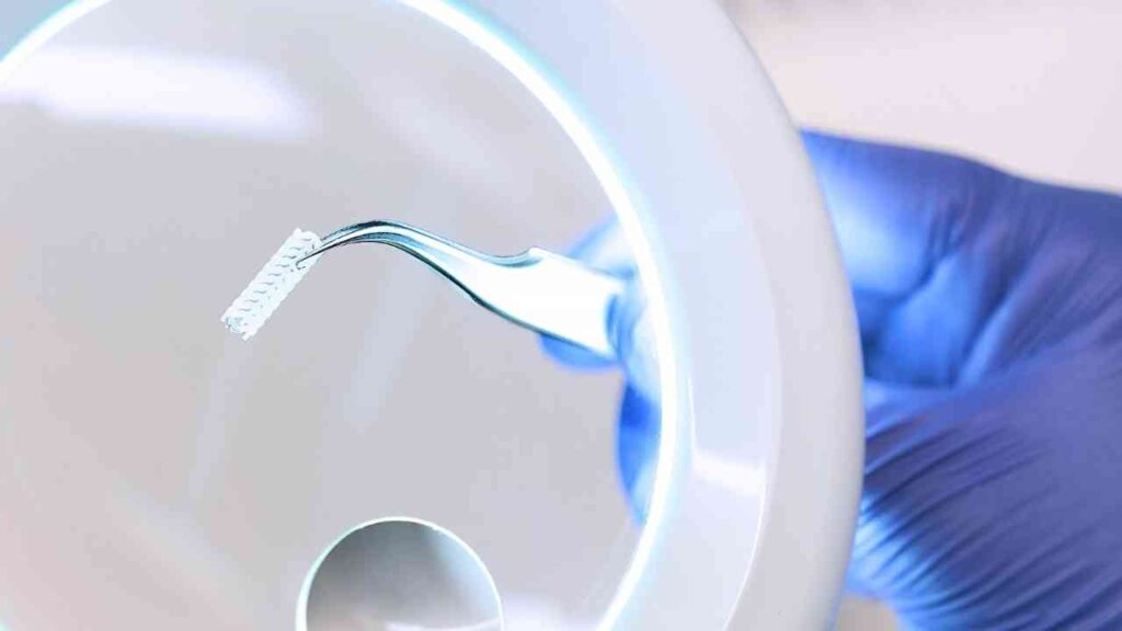 Nahaufnahme einer Pinzette mit Mikrochips unter einer Lupe. Laboruntersuchungstechnologie, präzise Wissenschaft.