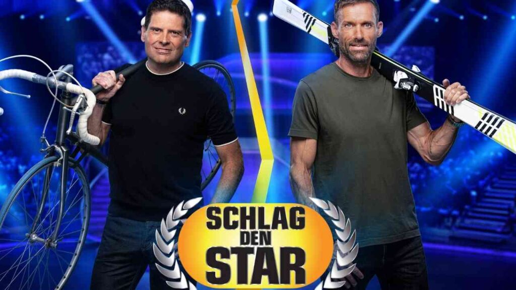 Zwei Männer stehen mit einem Fahrrad und einem Skisportgerät auf einer Bühne bei der Show 'Schlag den Star'.