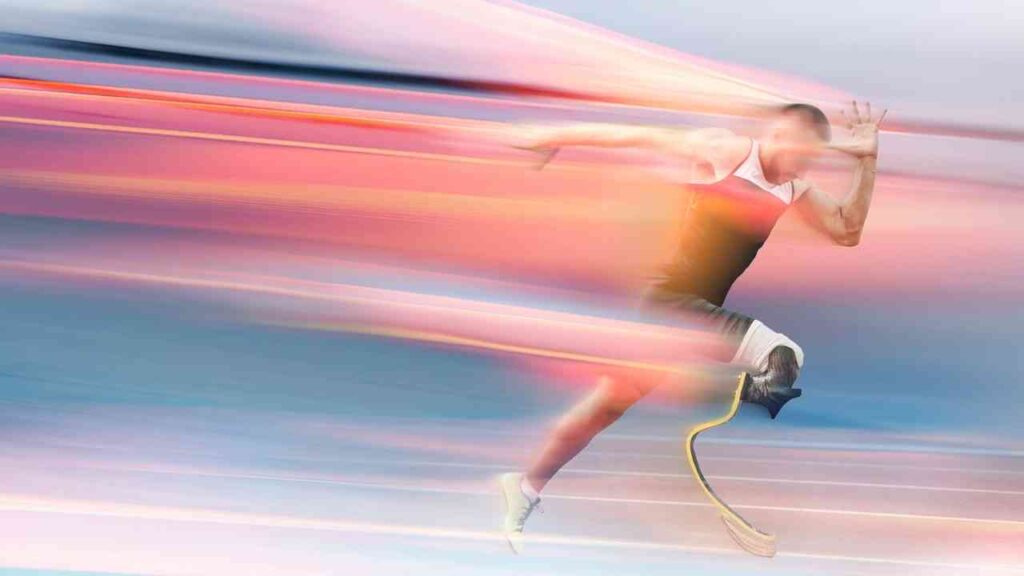 Ein Para-Sportler sprintet auf einer Laufbahn mit Prothesenbeinen in einem dynamischen, verschwommenen Bild.