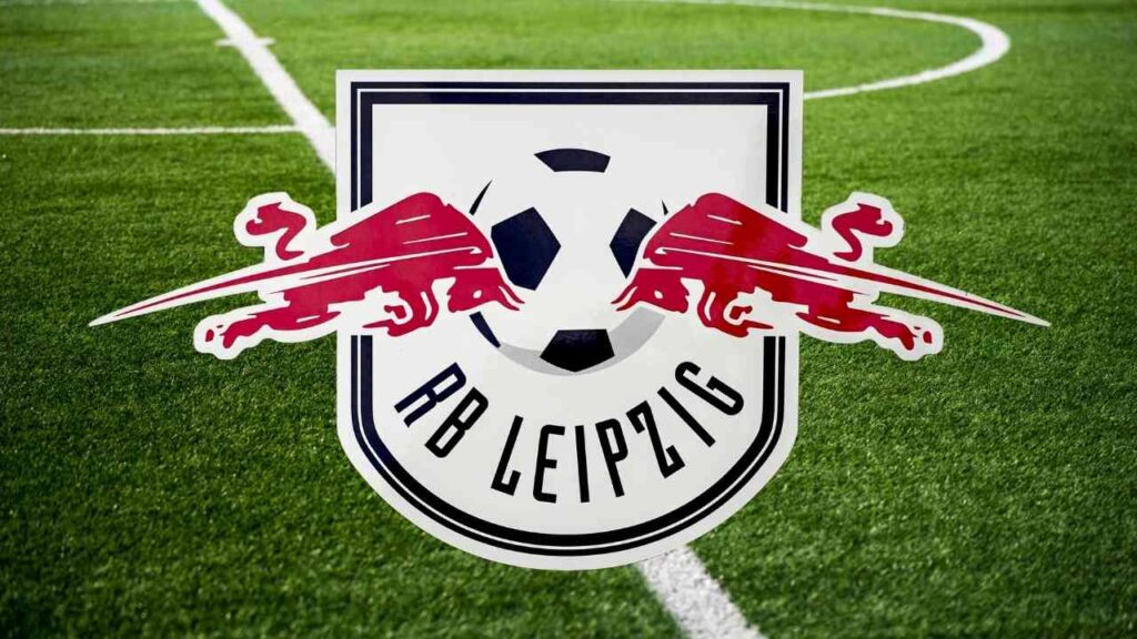 Logo von RB Leipzig mit einem Fußball und zwei roten Bullen auf grünem Rasen.