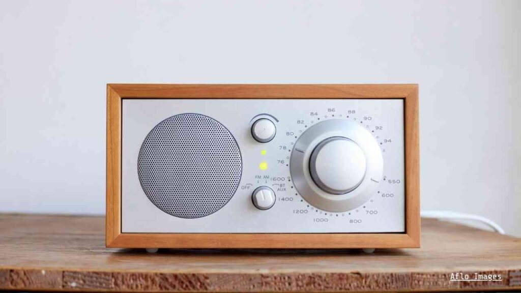 Holzrahmen-Radio mit analogem Tuner und Lautstärkeregler auf einem Tisch.