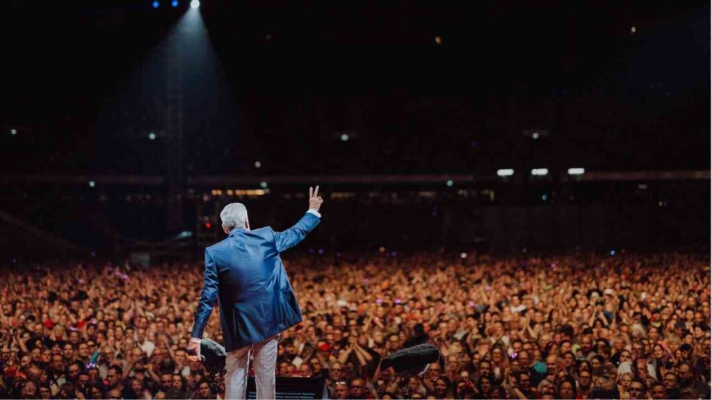 Roland Kaiser auf der Bühne vor einer großen Menschenmenge während eines Konzerts.