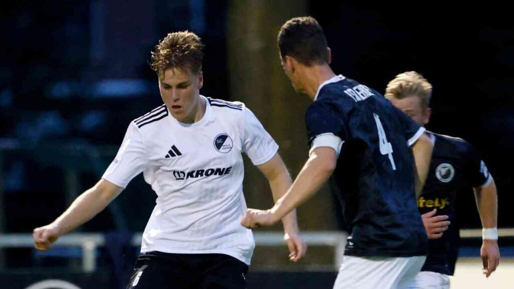 Zwei Fußballspieler im Wettkampf während eines Spiels, einer in einem weißen Trikot und der andere in einem dunklen Trikot.