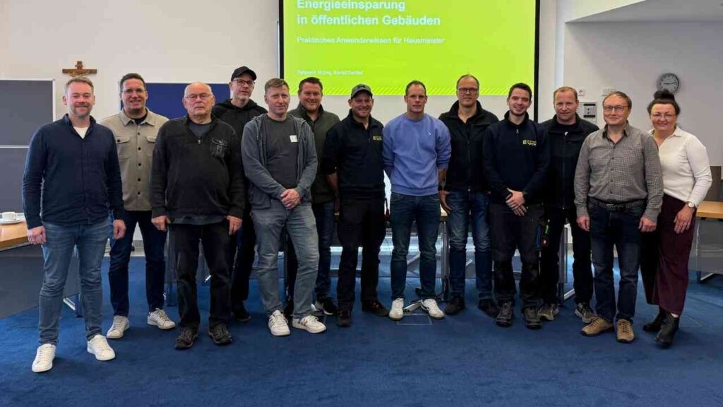 Gruppe von Personen, die an einer Schulung für Hausmeister in Spelle teilnehmen, stehen zusammen in einem Raum.