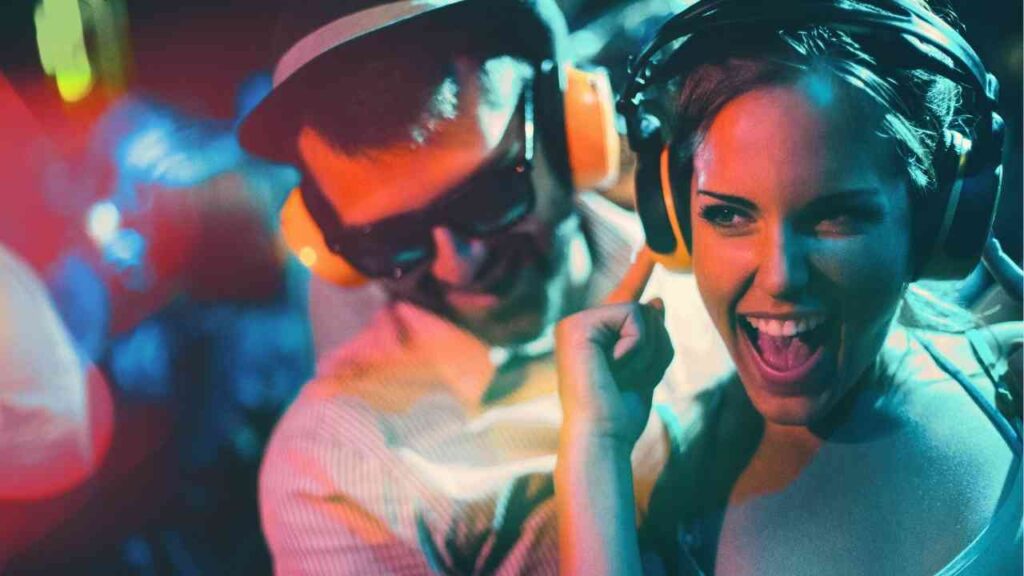 Zwei Personen mit Kopfhörern auf einer Silent Party, lächelnd und tanzend in einer lebhaften Umgebung.