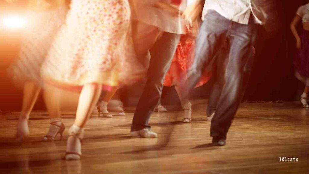 Tanzende Personen mit farbenfrohen Kleidern und Schuhen auf einer Tanzfläche während einer Veranstaltung.