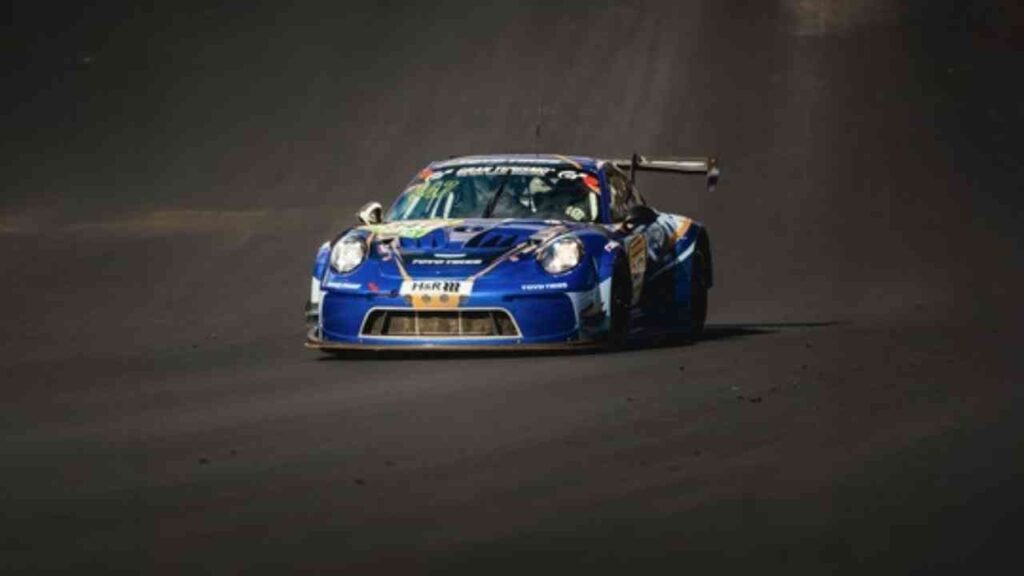 Blauer Porsche 911 GT4 EVO Rennwagen fährt auf einer Rennstrecke mit hoher Geschwindigkeit.