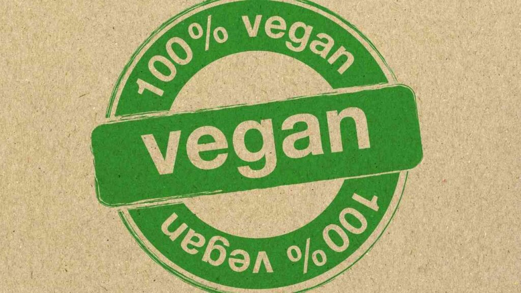 Grünes Siegel mit der Aufschrift '100% vegan' auf einem braunen Hintergrund.