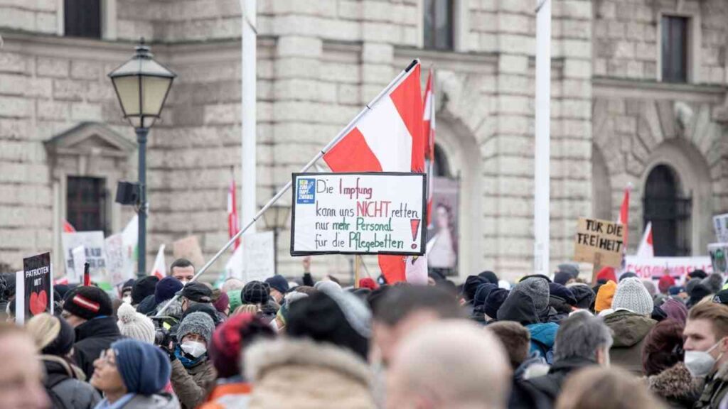 Menschenmenge bei einer Demonstration mit einem Schild, das die Aussage zur Impfung enthält.