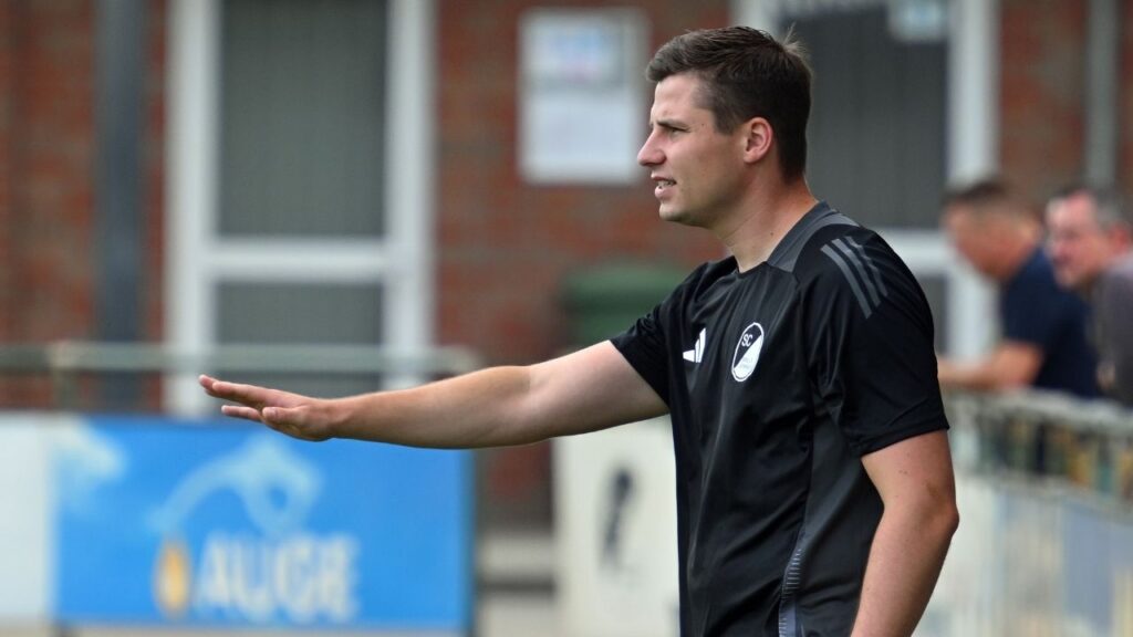 Trainer Henry Hupe gibt Anweisungen während eines Fußballspiels auf dem Platz.
