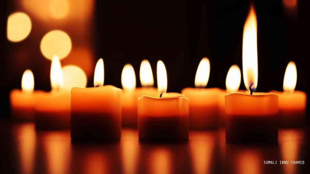 Eine Reihe von brennenden Kerzen mit warmem Licht auf einem dunklen Hintergrund.