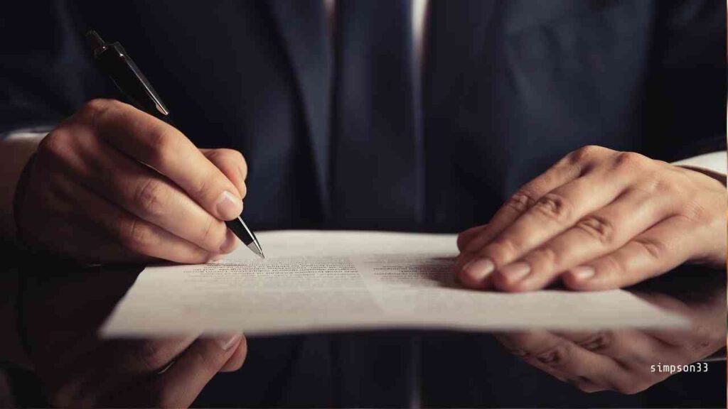 Mann in Anzug, der mit einem Stift auf einem Dokument schreibt, Hände auf dem Tisch platziert.