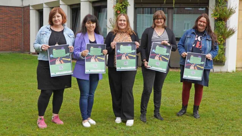 Organisatorinnen präsentieren Veranstaltungsplakat