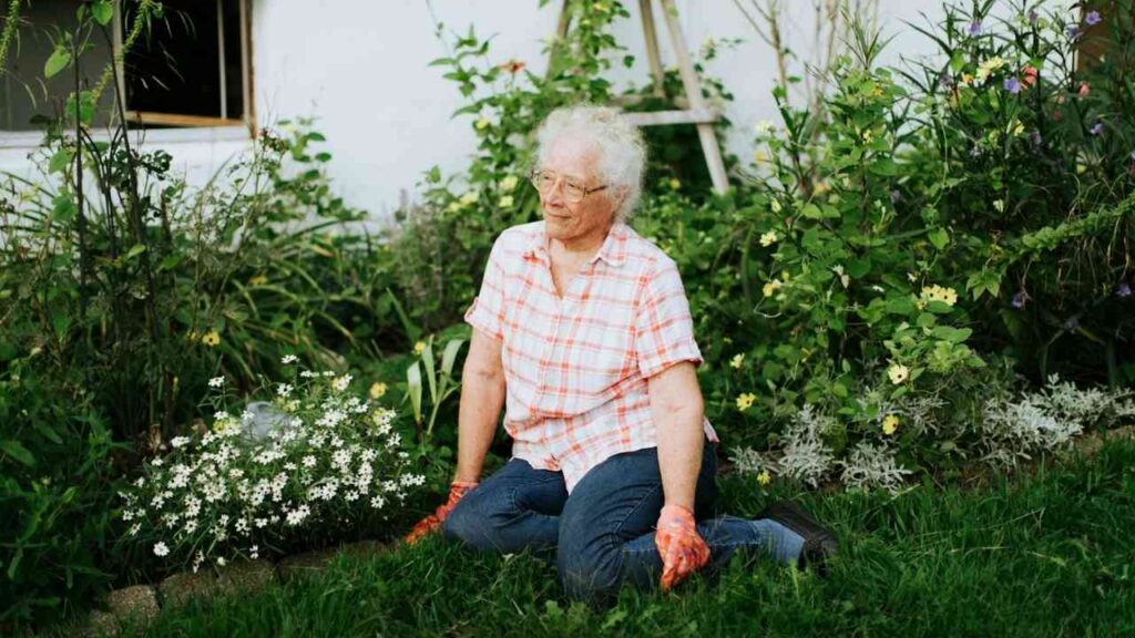 Ältere Frau sitzt auf einer Wiese und ruht sich aus