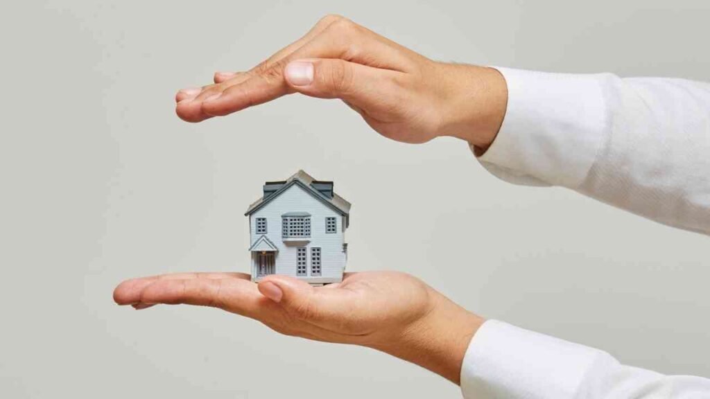 Hände, die ein kleines Modell eines Hauses halten, symbolisieren Schutz und Sicherheit für Immobilien.