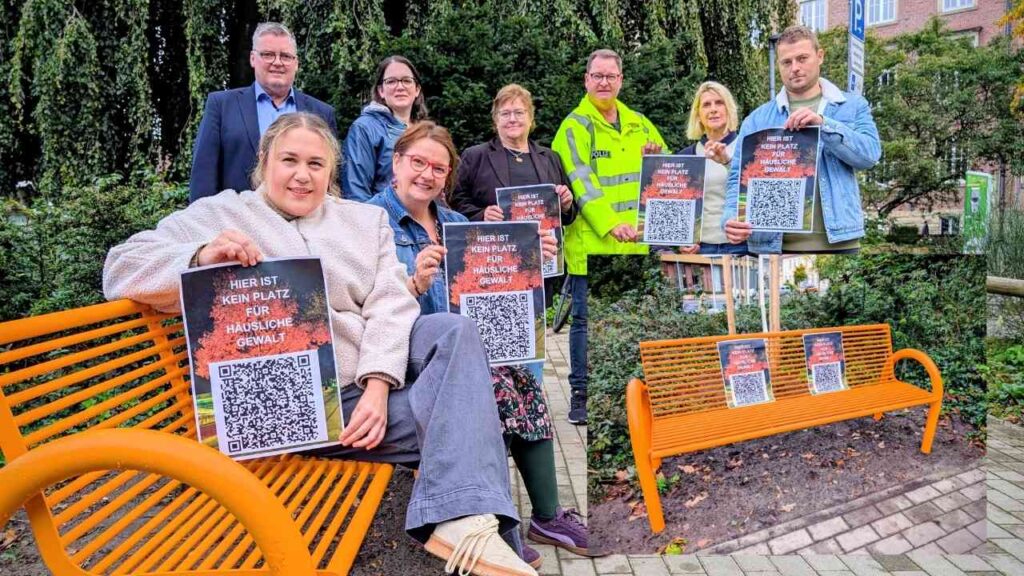 Eine orangefarbene Bank im Freien, umgeben von Menschen, die Plakate halten.