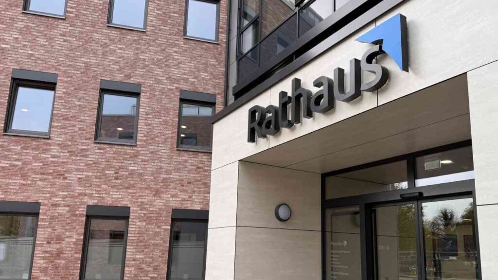 Eingang zum Rathaus mit dem Schriftzug 'Rathaus' an der Fassade eines modernen Gebäudes.