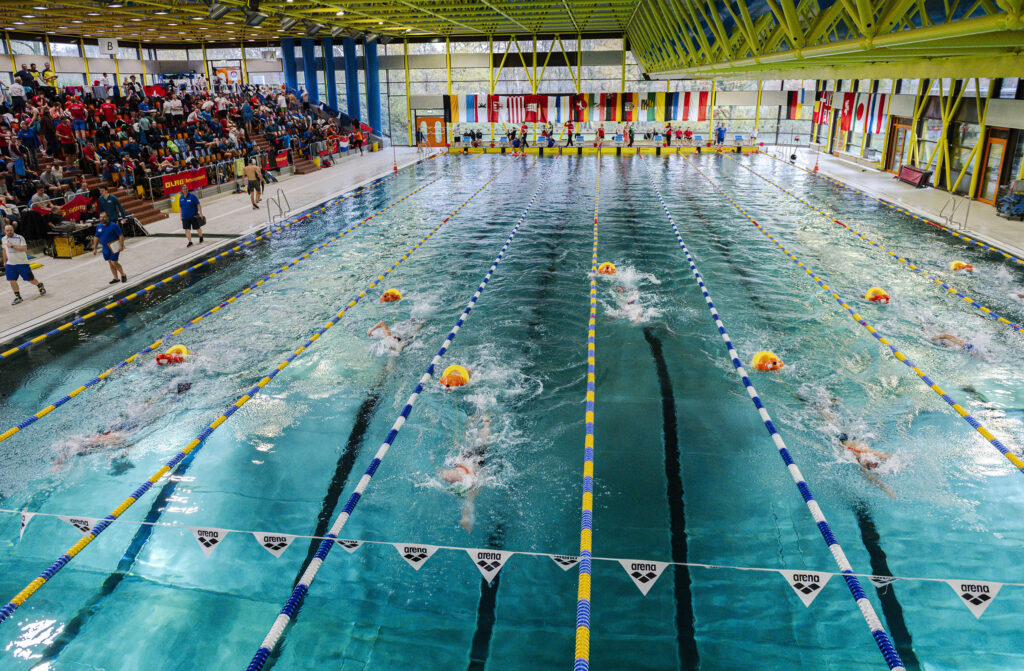 Schwimmwettkampf in einem Hallenbad mit mehreren Schwimmern, die um den Sieg kämpfen.