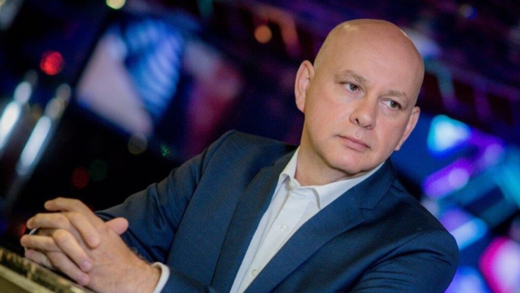 Mann mit Glatze in einem blauen Anzug, der nachdenklich in die Ferne blickt.