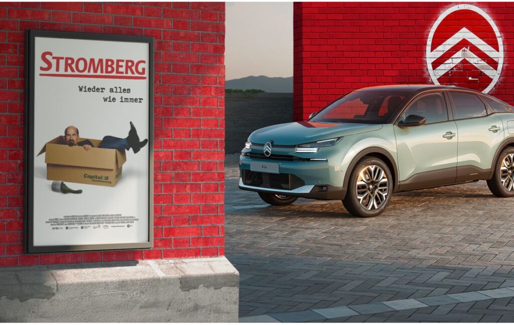 Ein Werbeplakat für die Serie 'Stromberg' neben einem modernen Auto in einer urbanen Umgebung.