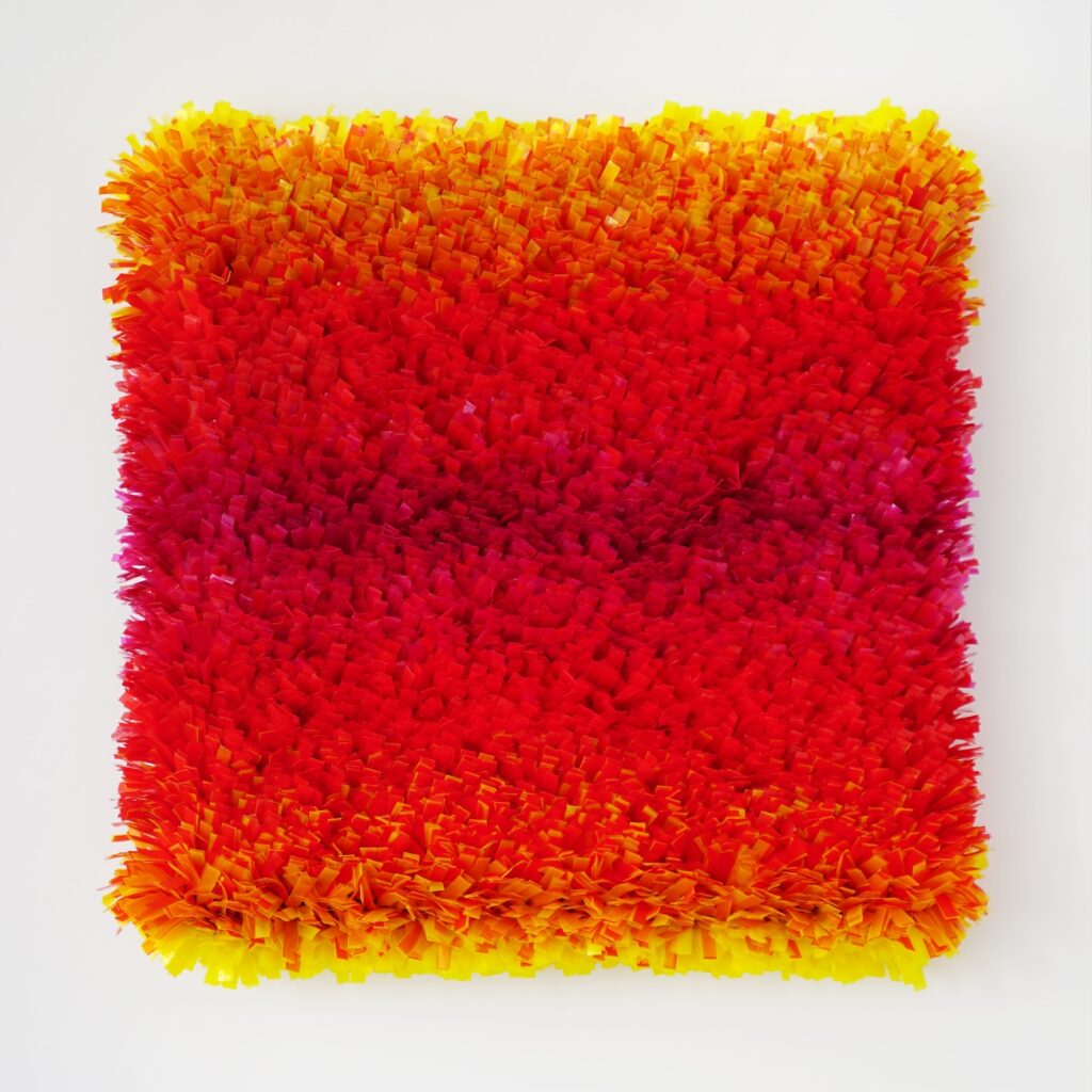 Texturiertes Kunstwerk in Rot- und Gelbtönen mit fransigen Elementen, die eine lebendige Farbverlaufsgestaltung zeigen.